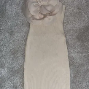 Elegantna bež haljina s velikim cvetnim detaljem