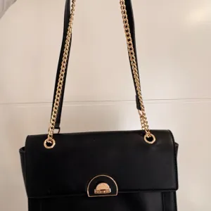 Elegantna crna torbica sa zlatnim detaljima