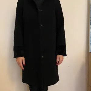 Crni kaput sa krznenim detaljima