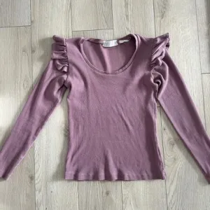 Rebrasta bluza sa volanima na ramenima