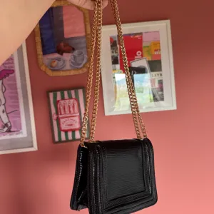 Mala crna lakovana torba- Carpisa