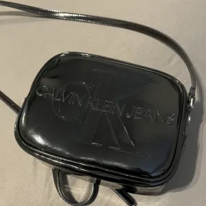 POTPUNO NOVA Calvin Klein torbica LAKIRANA CRNA